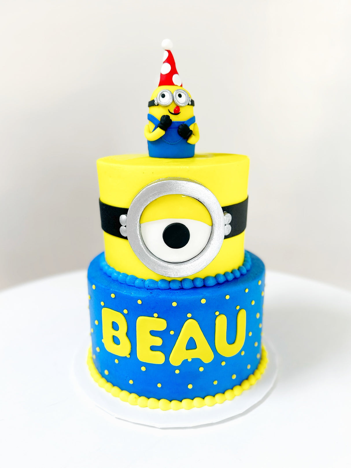 Customized Cake (2-Tier Minion Design with Buttercream, Sculpted Minion, and Fondant Accents)